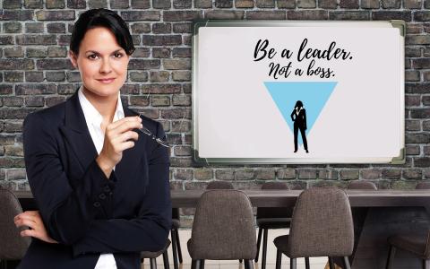 Business woman with a white board that states, "Be a leader and not a boss"
