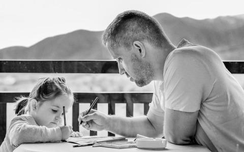 Co-parenting father helping daughter at the table