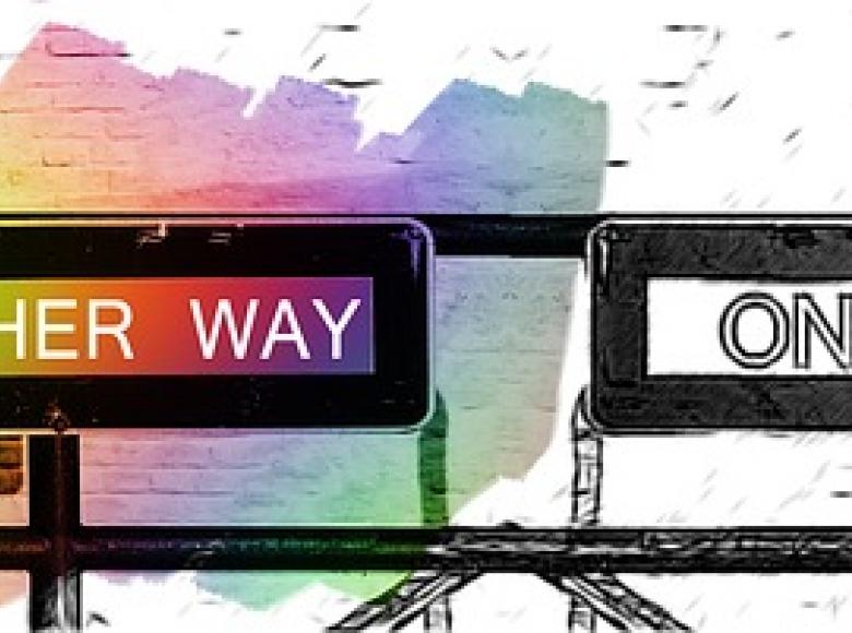 A one way sign in black and white pointing right and a one way sign in color pointing left