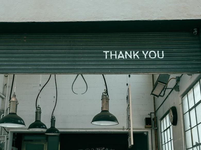 Thank you on a steel garage door security panel in a partially opened state with lamps hanging from the ceiling