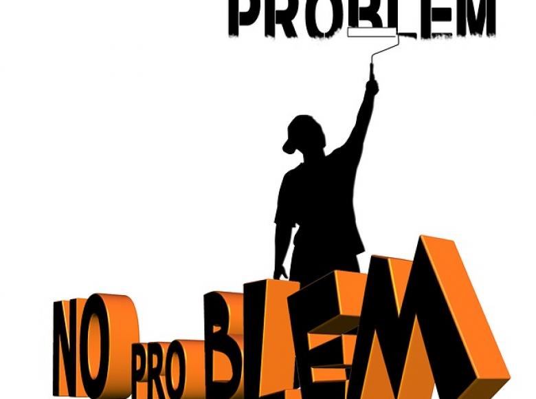 Person with paint roller painting over the word "Problem" and standing in front of the words "No Problem"
