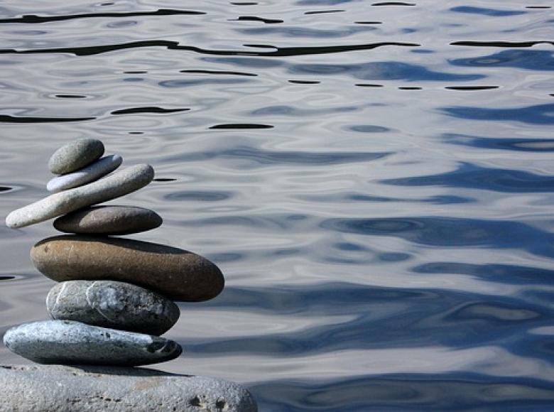 Eight rocks balanced on each other with water in the background