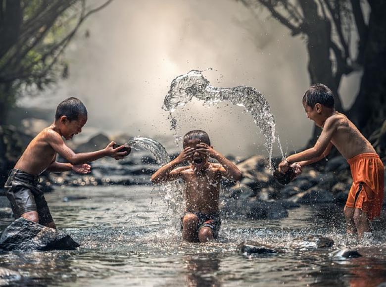 Three children splashing each other in a river