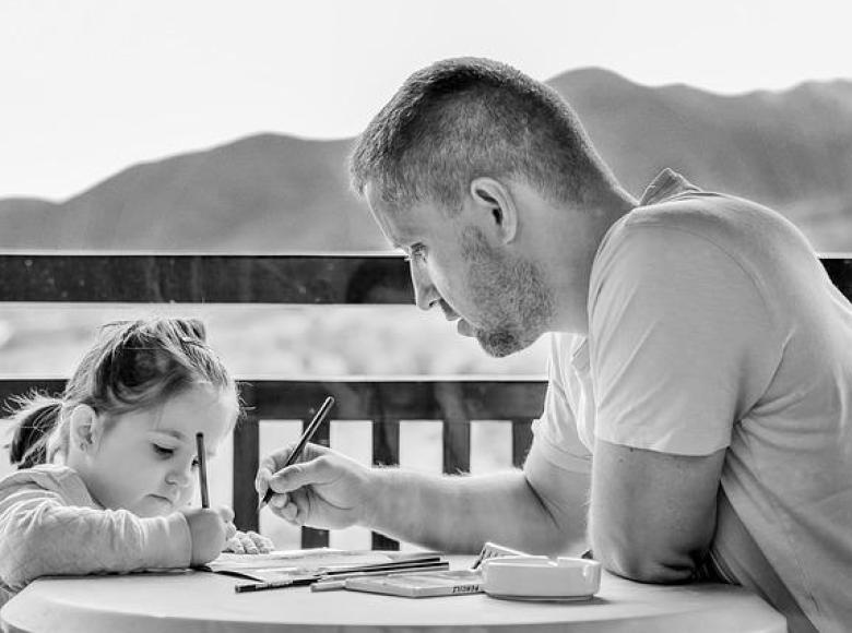Co-parenting father helping daughter at the table