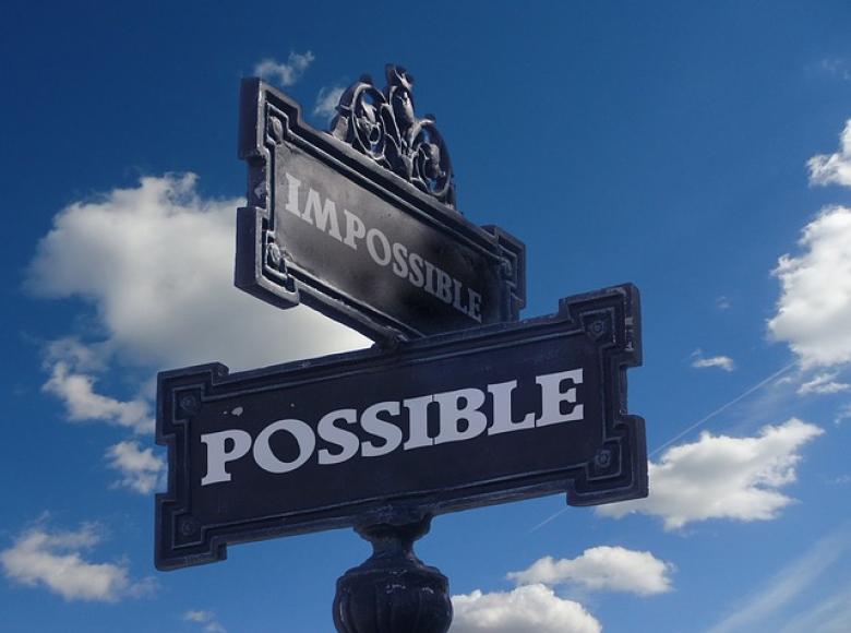 A street sign at the intersection of Impossible and Possible with a background blue sky with some white clouds