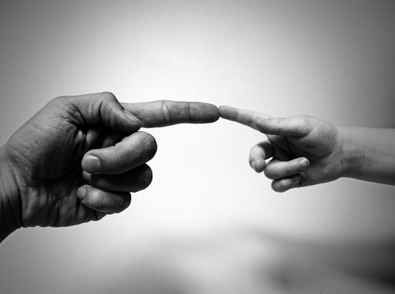 Two hands reaching out to each other and touching with the first finger