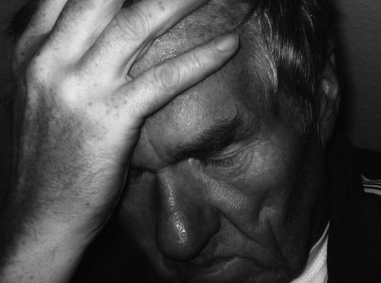 Man looking down with hand on his forehead looking very distraught