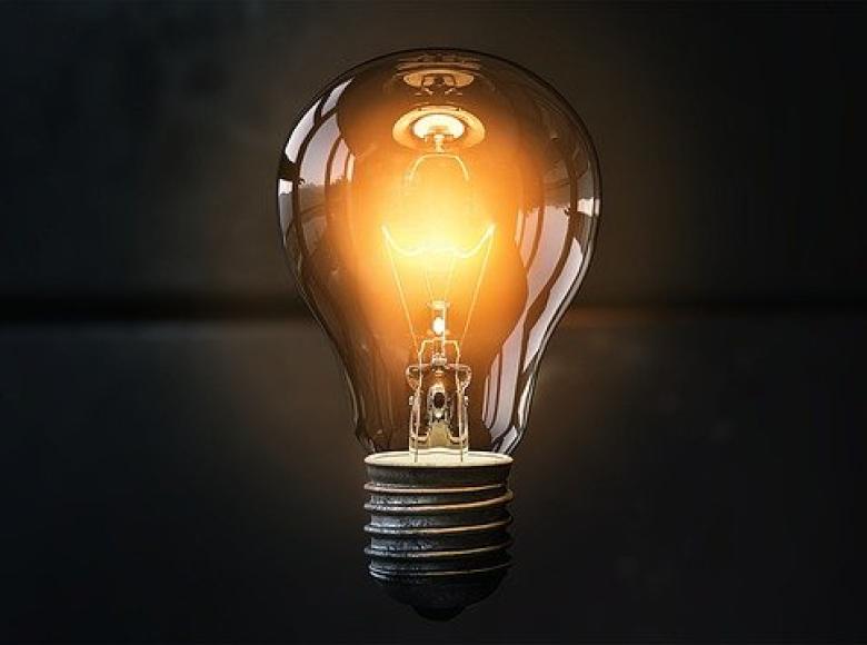 A lit light bulb with a black background