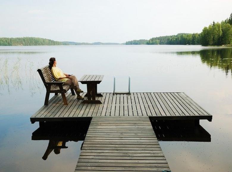 Woman sitting on a dock with a view of a very peaceful lake