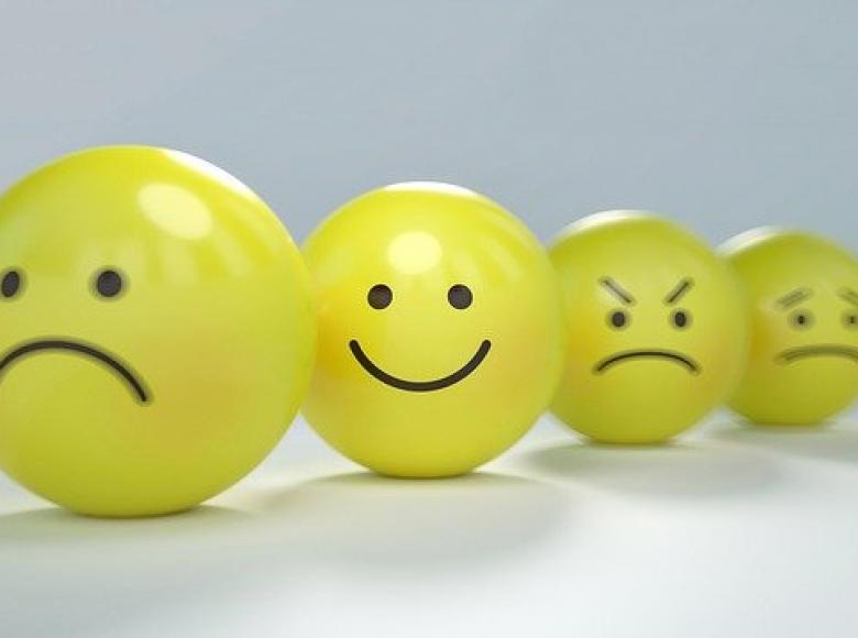 Four yellow smiley face ping pong balls from sad, happy, angry, dismayed