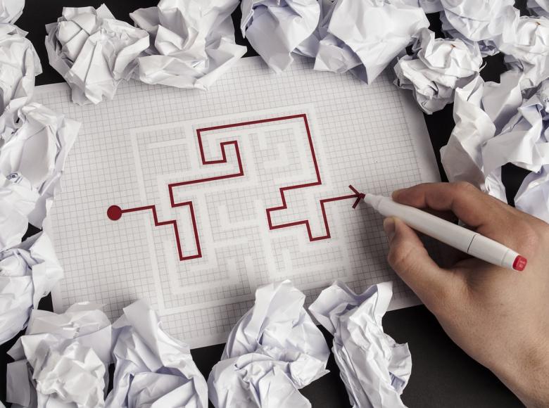 A person using a pen to map their way through a puzzle